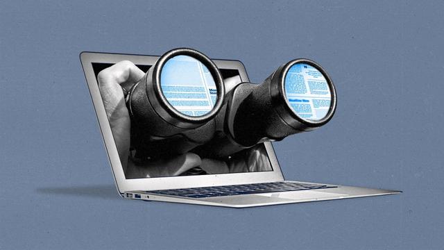 A pair of hands holds binoculars through a laptop, with the reflection of news websites in the lenses.
