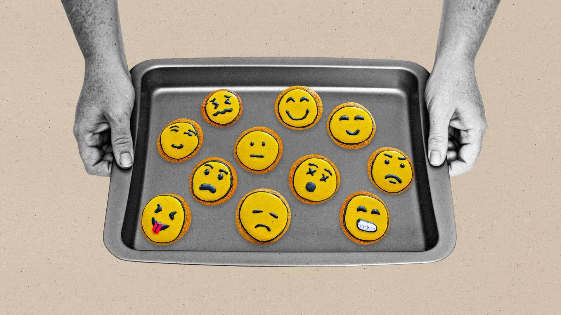 Two hands hold out a cookie sheet filled with cookies with icing toppings showing various reactions.