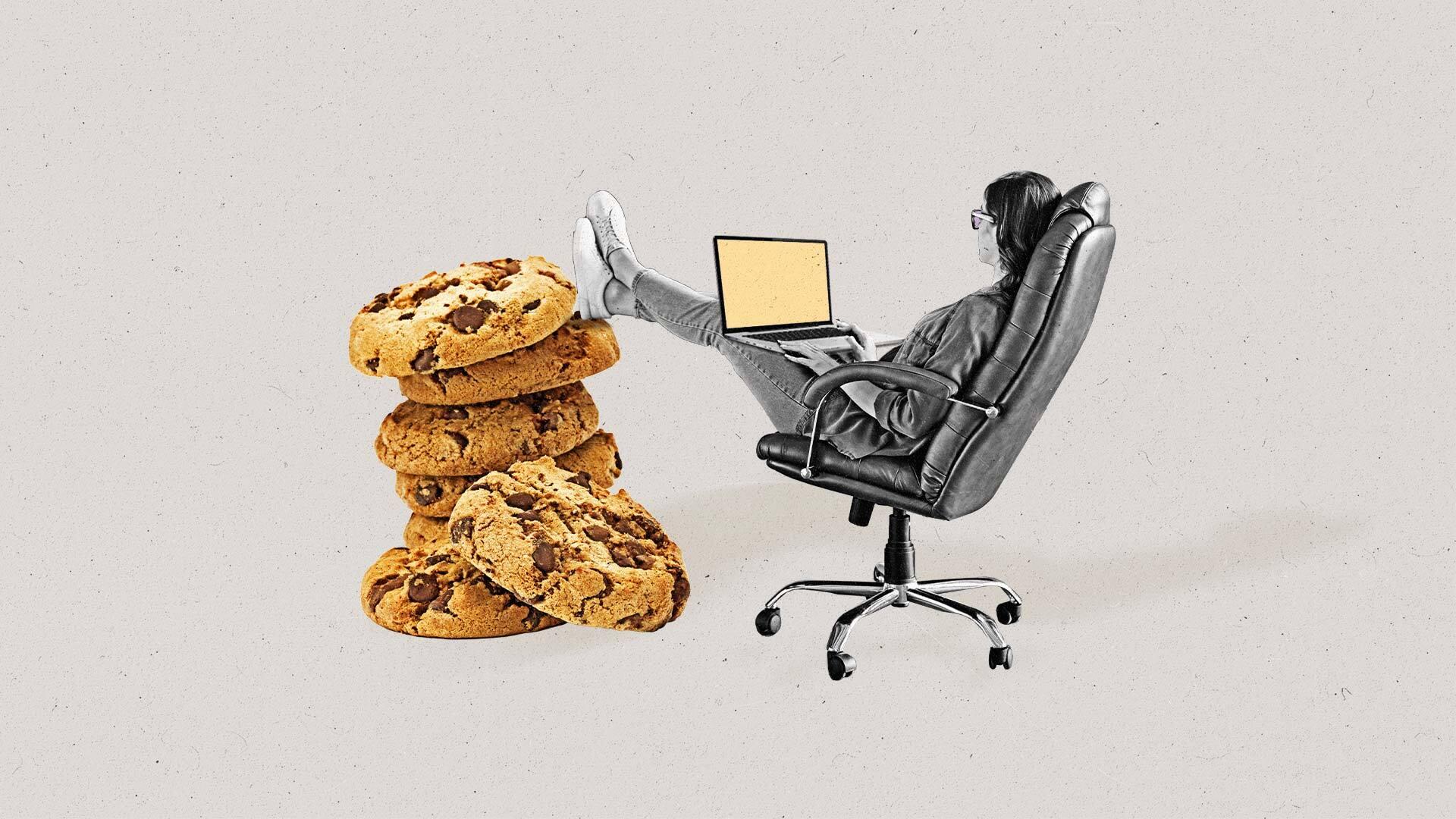 Businesswoman works on laptop and rests feet on stack of cookies.
